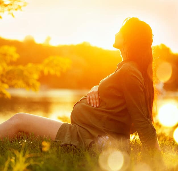 Pregnant Woman in the grass at Sunset