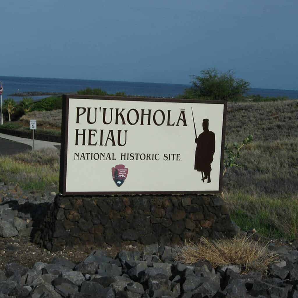 Puʻukoholā Heiau National Historic Site signage with a silhouette of King Kamehameha I with a view of sea from afar