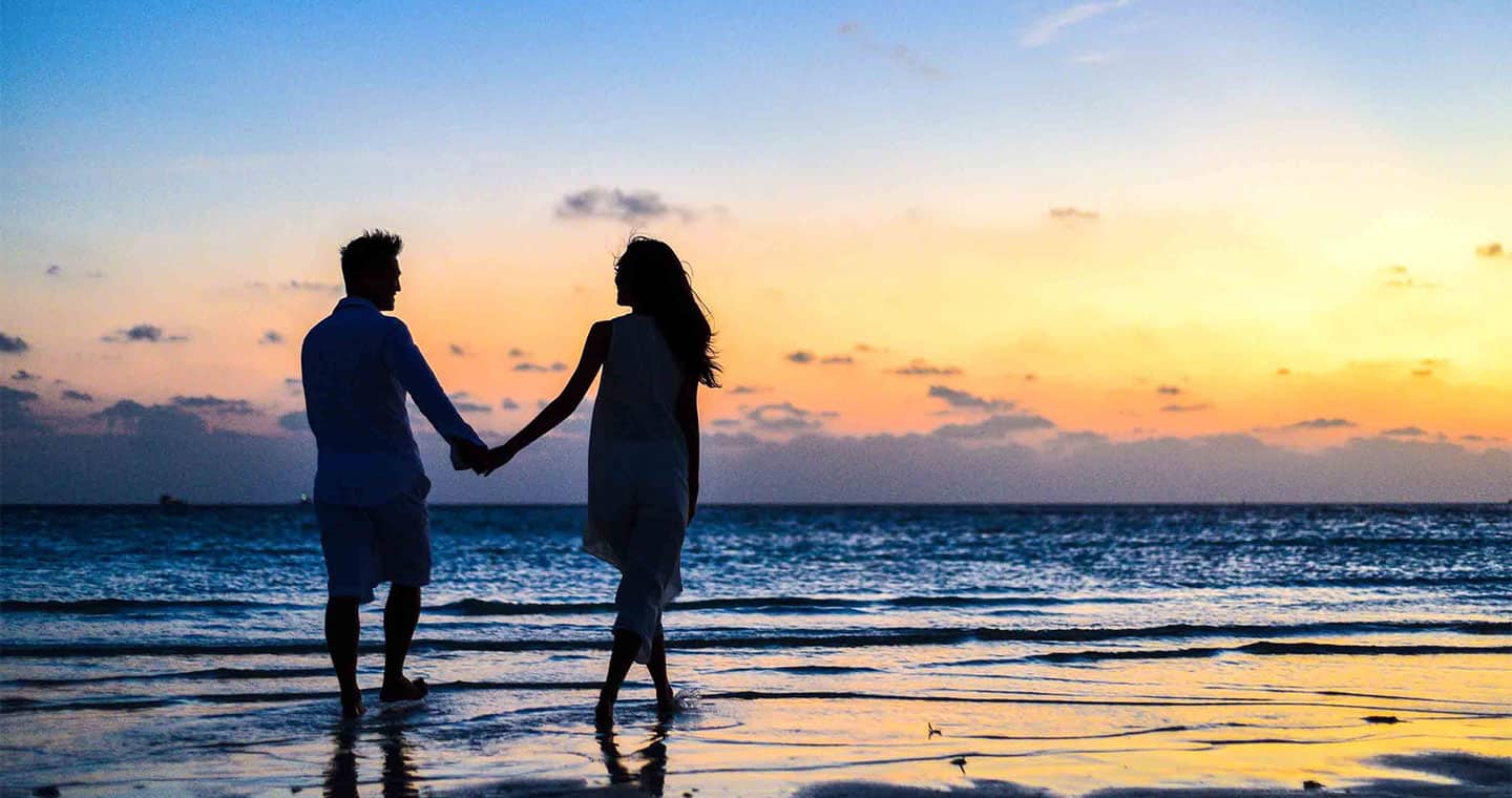 A couple holding hand at the beach during their Hawaii honeymoon