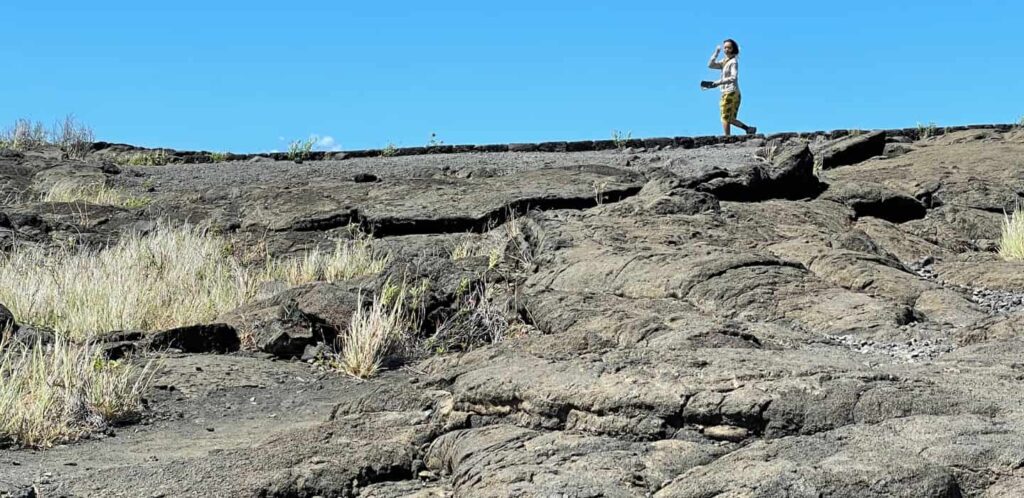 Woman walking the epic petroglyph trail. Embark on this Hawaii historic journey yourself while staying at our Volcano lodging.