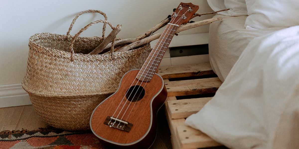 A ukulele leaning on a palette bed