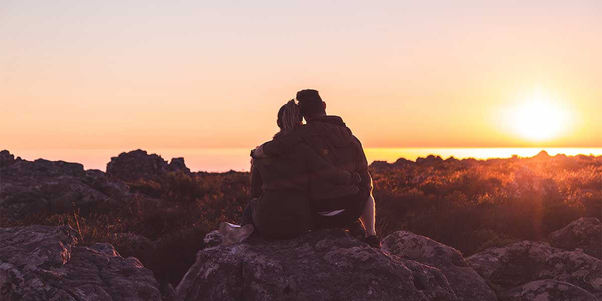 lovely couple watching the sunset after a hike