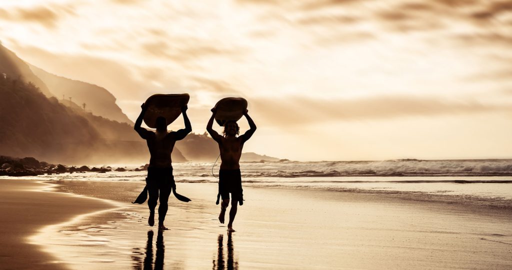 Surfers On Beach In Hawaii