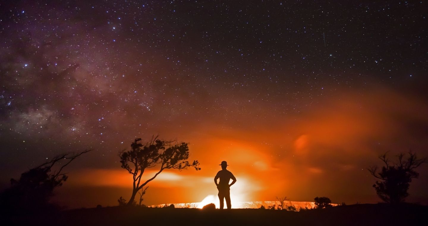 Park Ranger and night sky with glowing volcano at Hawaii Volcanoes National Park