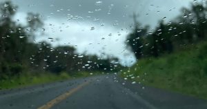 Looking through the windshield of a car driving down a road in Volcano during rainy season in Hawaii